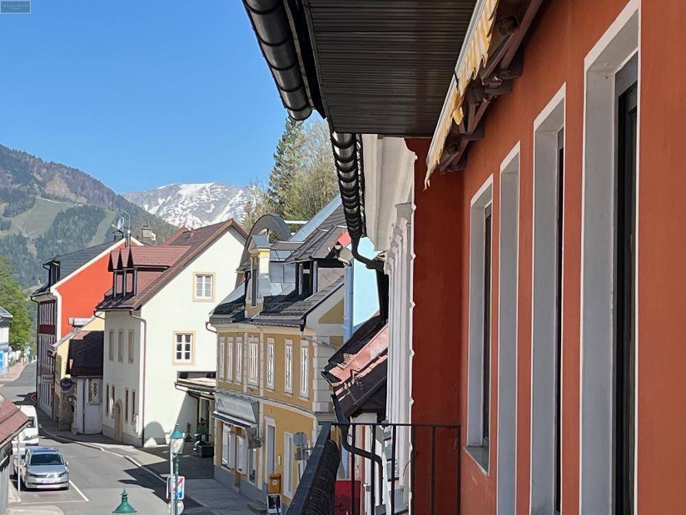 Balkon mit Blick auf eine malerische Straße und schneebedeckte Berge im Hintergrund, eine atemberaubende Aussicht.