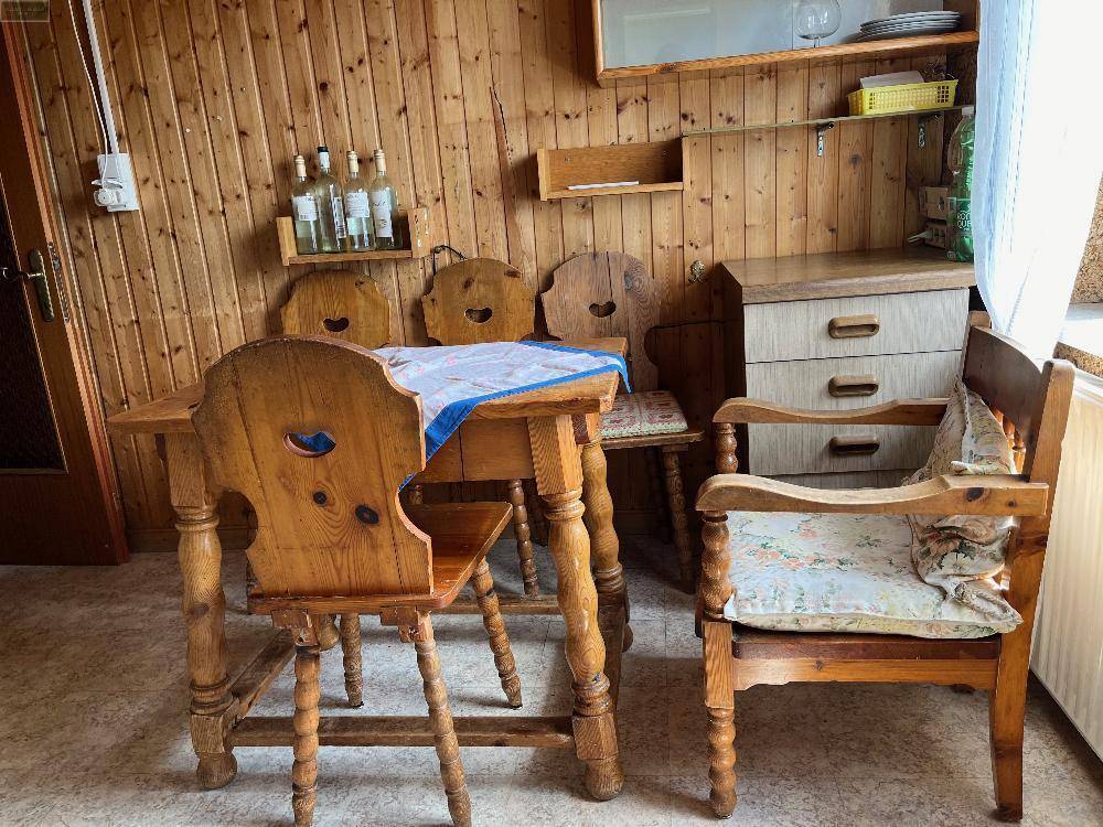 Rustikaler Essbereich in der Küche mit traditionellen Holzmöbeln und Holzvertäfelung an den Wänden.