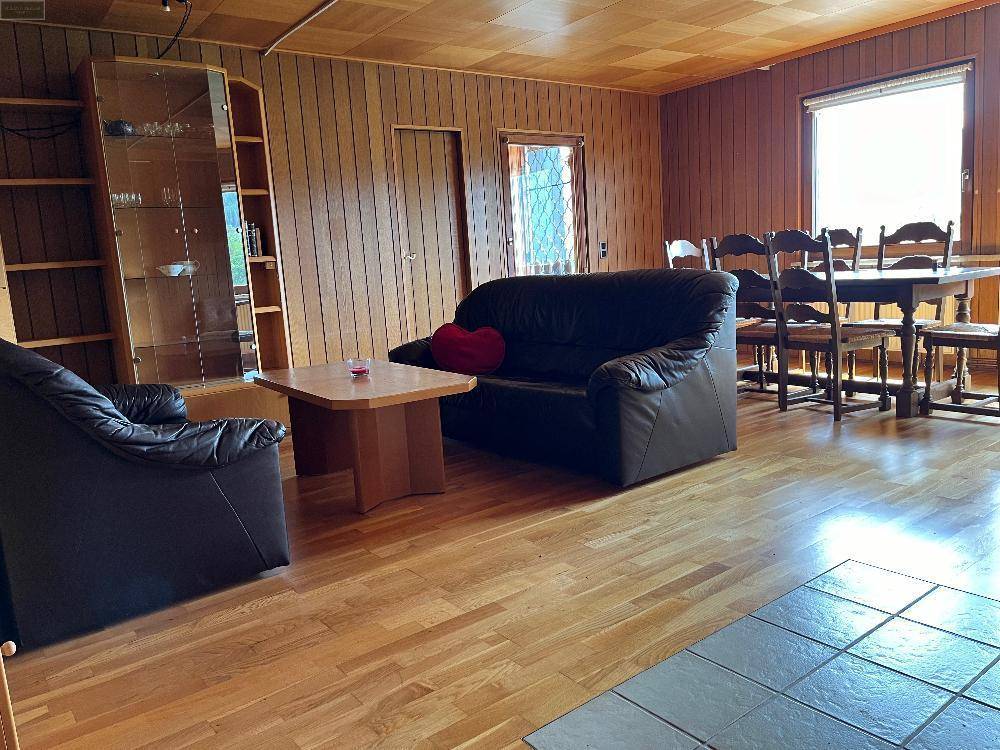 Großzügiger Wohn-Essbereich mit Ledersofas, Couchtisch, Esstisch und einer Vitrine.