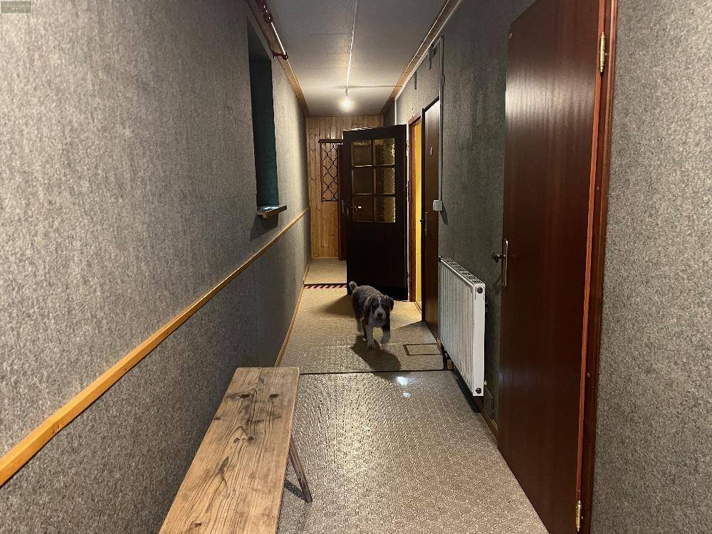 Langer Flur mit strukturierten Wänden, einer Holzbank und mehreren Türen zu den Zimmern.