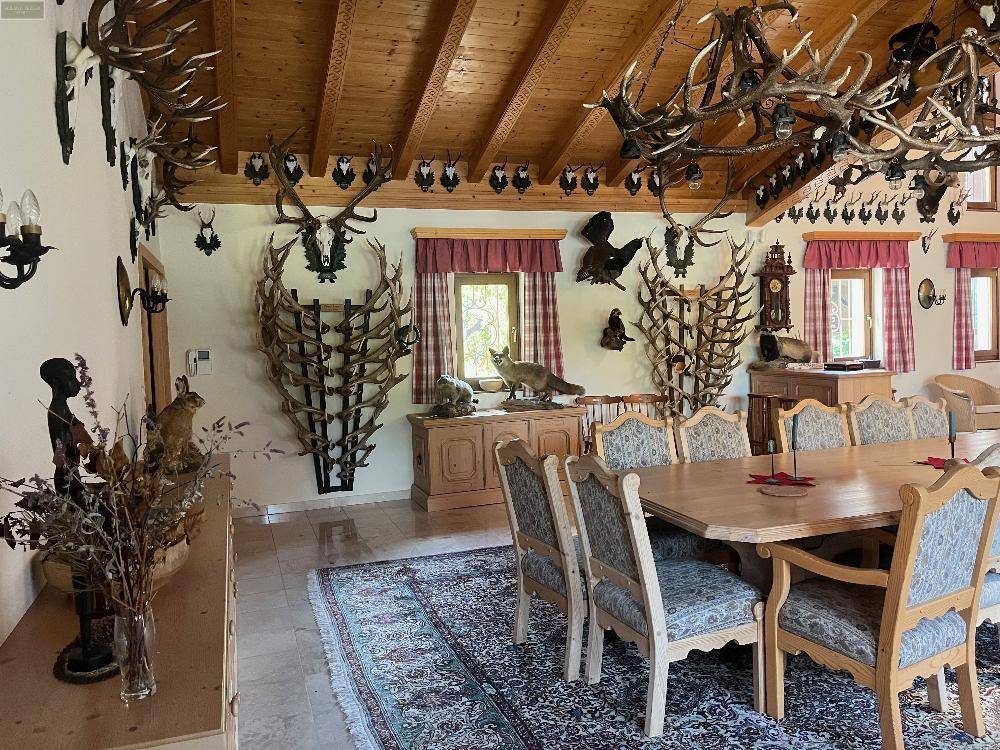 Detailansicht des Essbereichs mit traditionellen Möbeln und einer beeindruckenden Sammlung von Hirschgeweihen an den Wänden.