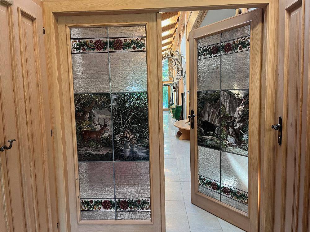 Traditionelle Holztüren mit kunstvollen Glaseinsätzen, die in einen hellen Innenbereich führen.