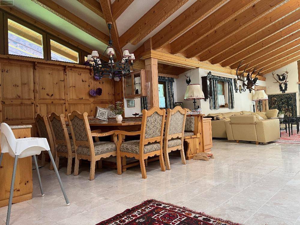 Essbereich mit rustikalem Holztisch und Stühlen, umgeben von Holzvertäfelung und traditioneller Dekoration.