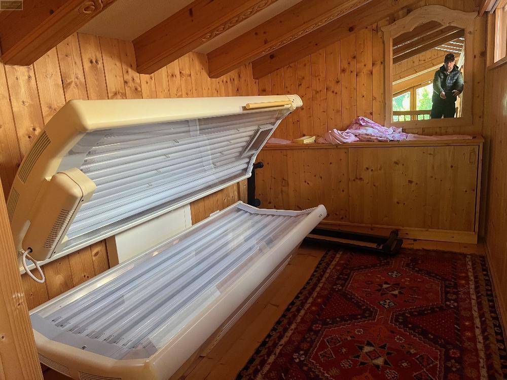 Raum mit Solarium, Holzwänden und einem Teppich, der als privater Wellnessbereich dient.