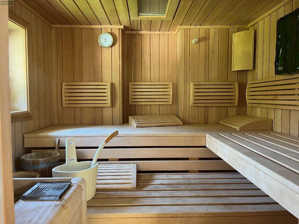 Traditionelle Holzsauna mit mehreren Bänken und typischem Zubehör für entspannende Wellnessmomente.