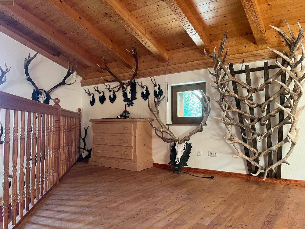Obergeschoss mit Holzboden und weiteren Hirschgeweihen als traditionelle Dekoration an den Wänden.