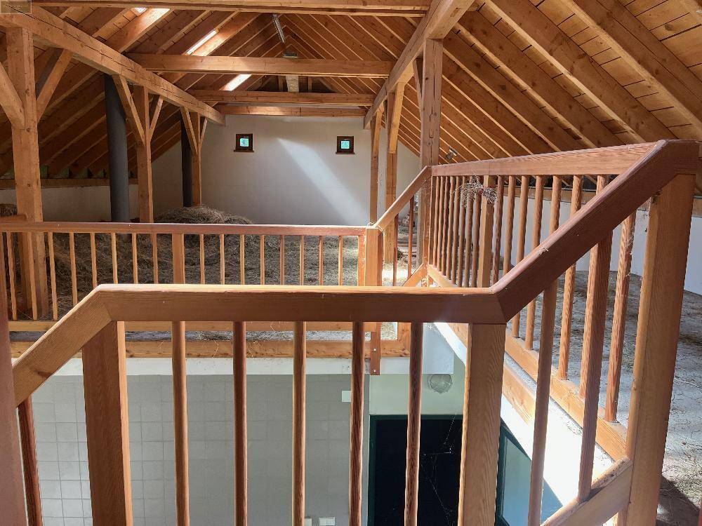Obergeschoss eines Scheunengebäudes mit sichtbaren Holzbalken und gelagertem Heu, rustikaler Charme.