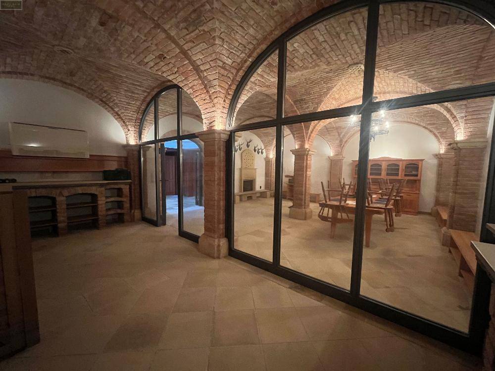 Gewölbekeller mit großen Glasfronten, die den Raum hell und offen wirken lassen, und rustikalen Möbeln.