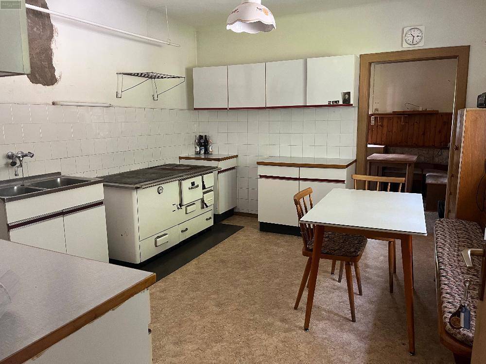 Küche im traditionellen Stil mit weiß-roten Schränken, Fliesenrückwand und einem Holzofen als Kochstelle.