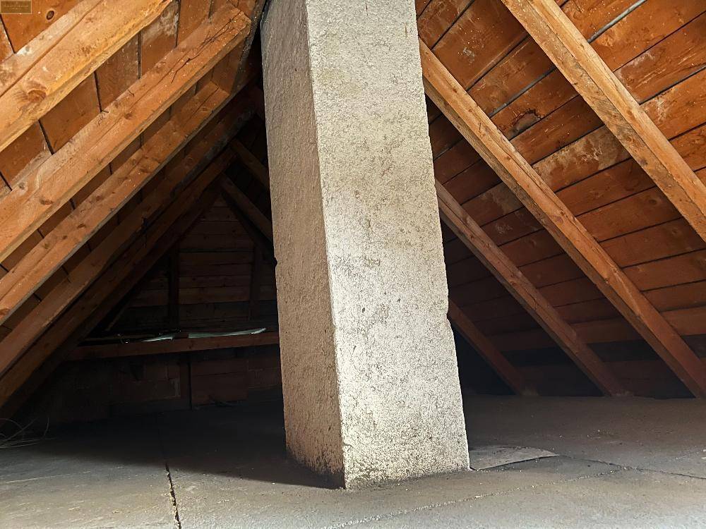 Unausgebauter Dachboden mit sichtbaren Holzbalken und schräger Dachkonstruktion, ideal für Ausbau.