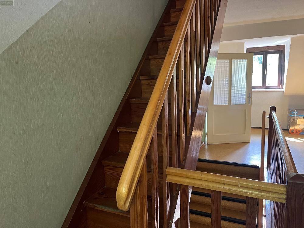 Helle Holztreppe mit Geländer, die zu den oberen Etagen führt, in einem traditionellen Stil.