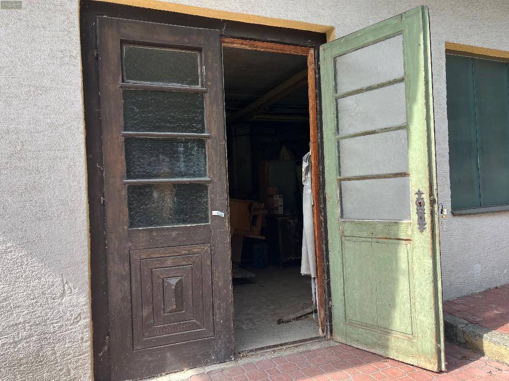 Eingang zu einem Werkstattbereich mit alten Holztüren und Blick ins Innere.