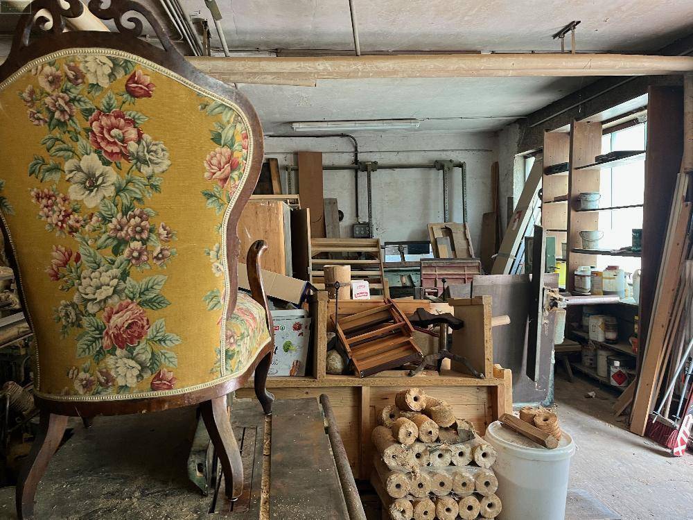 Werkstattraum mit einem antiken Stuhl, Holzmaterialien und Werkzeugen.