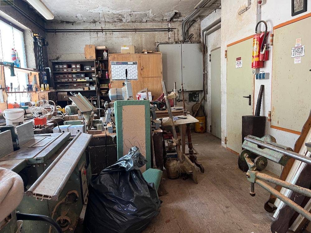 Großer Werkstattraum mit Arbeitsflächen, Regalen und verschiedenen Geräten.