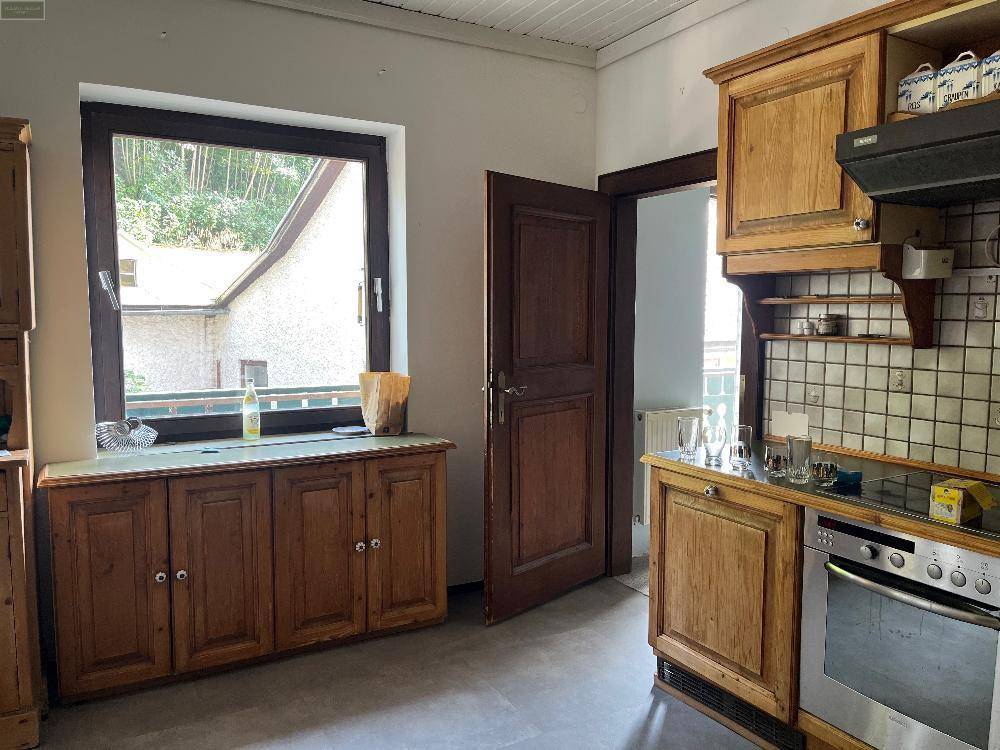 Traditionelle Holzküche mit Einbaugeräten und Fenster, das einen Blick ins Grüne bietet.