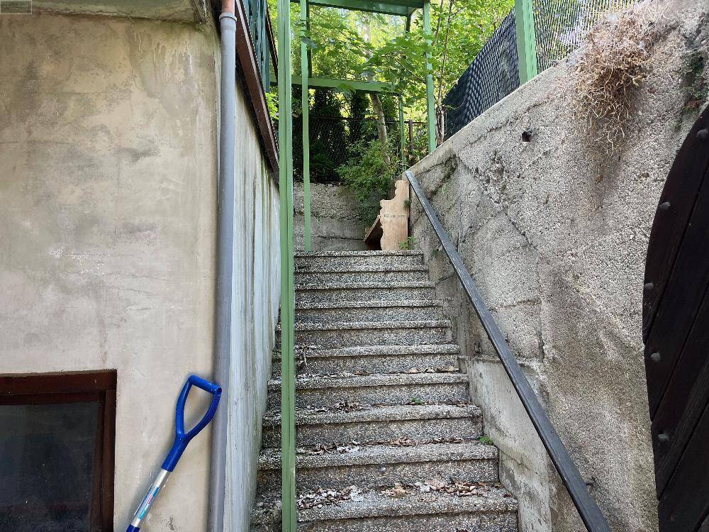 Steintreppe im Außenbereich, die zu einem höher gelegenen Gartenbereich führt, mit robusten Mauern.