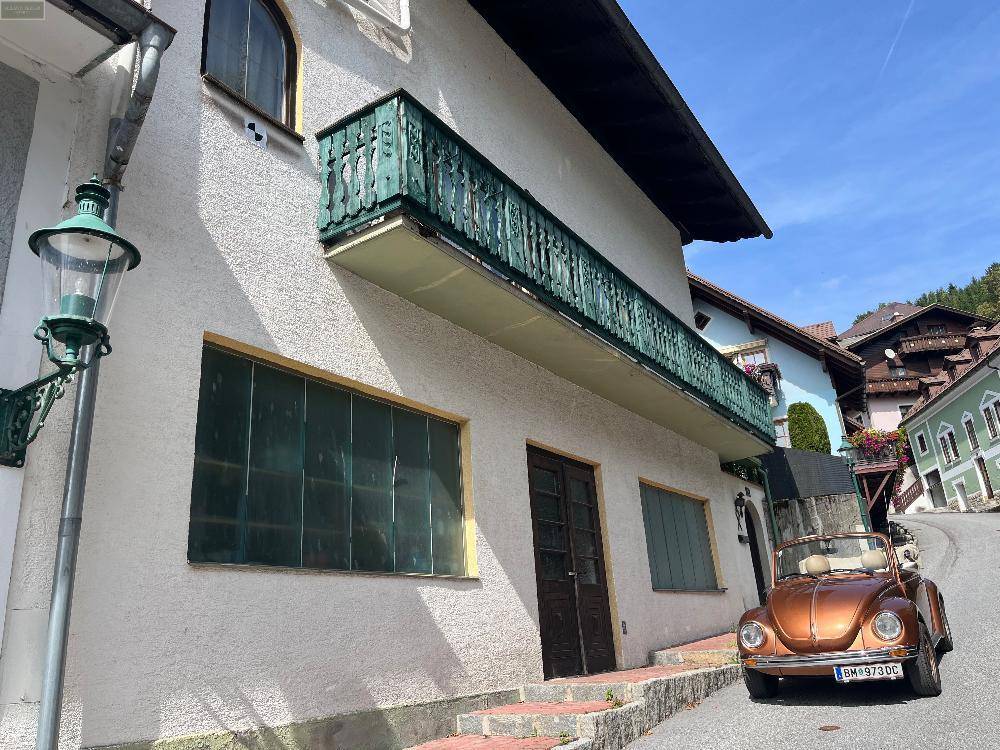 Detailansicht der Hausfassade mit grünem Balkon und historischem Charme, eingebettet in die Landschaft.