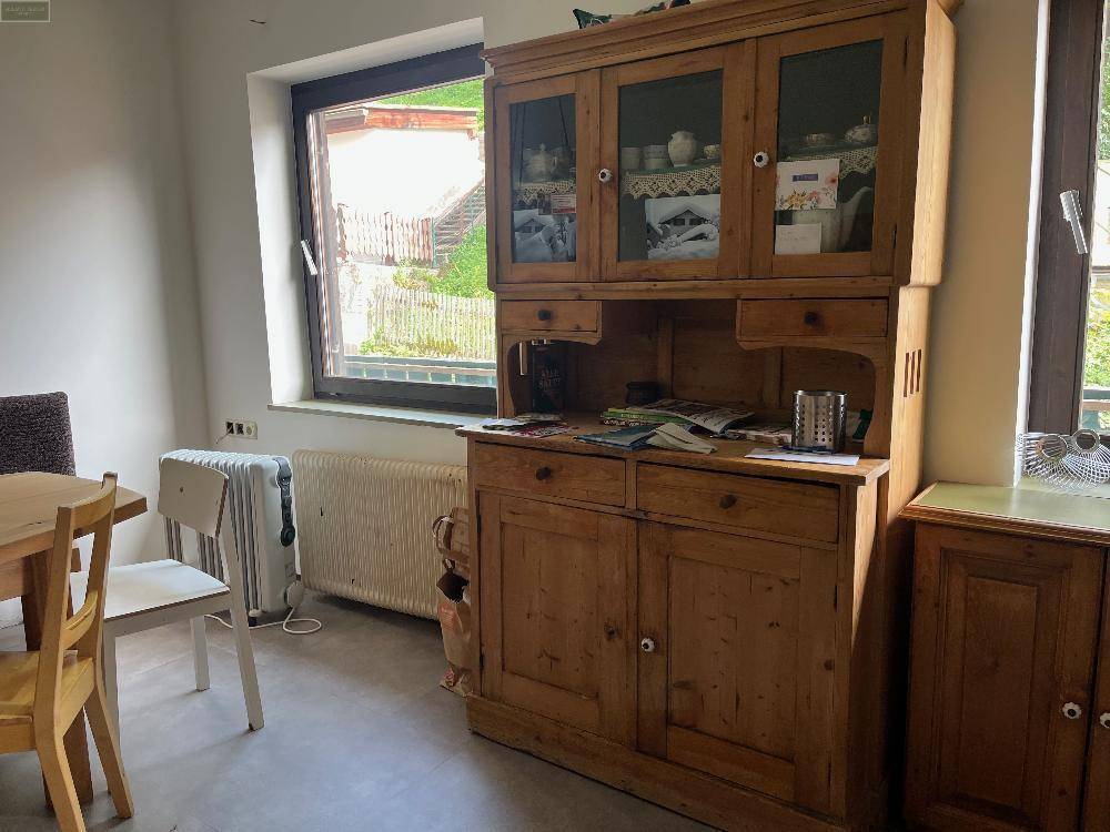 Gemütlicher Essbereich mit Holzschrank und Fenster, das viel Tageslicht hereinlässt und eine angenehme Atmosphäre schafft.