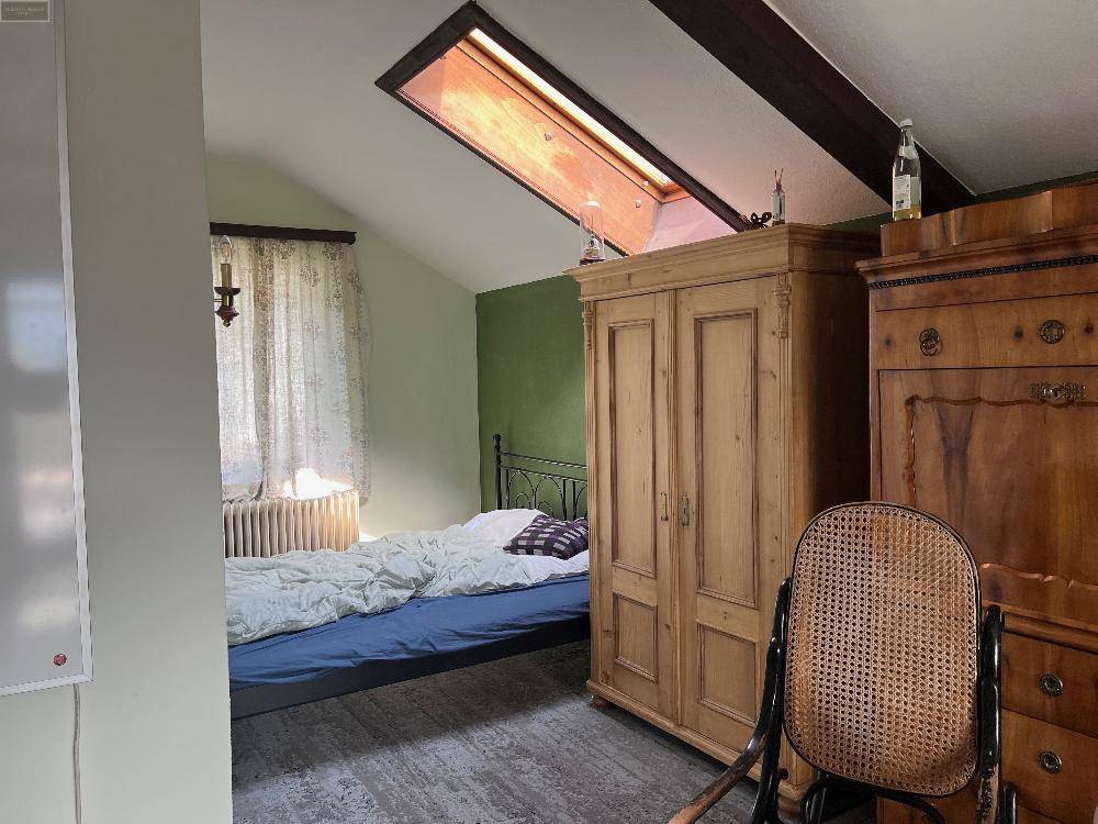 Schlafzimmer mit Dachschräge, Holzbalken und Dachfenster für natürliches Licht und eine gemütliche Atmosphäre.