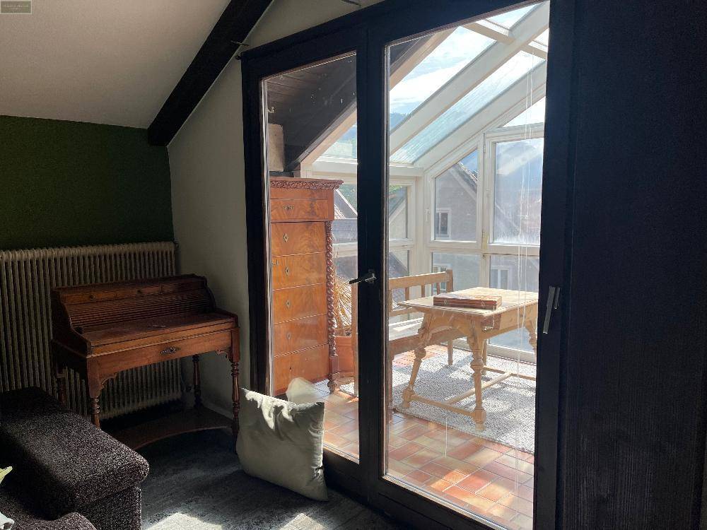 Blick vom Innenraum durch eine Glastür in den hellen Wintergarten, der viel Licht spendet.