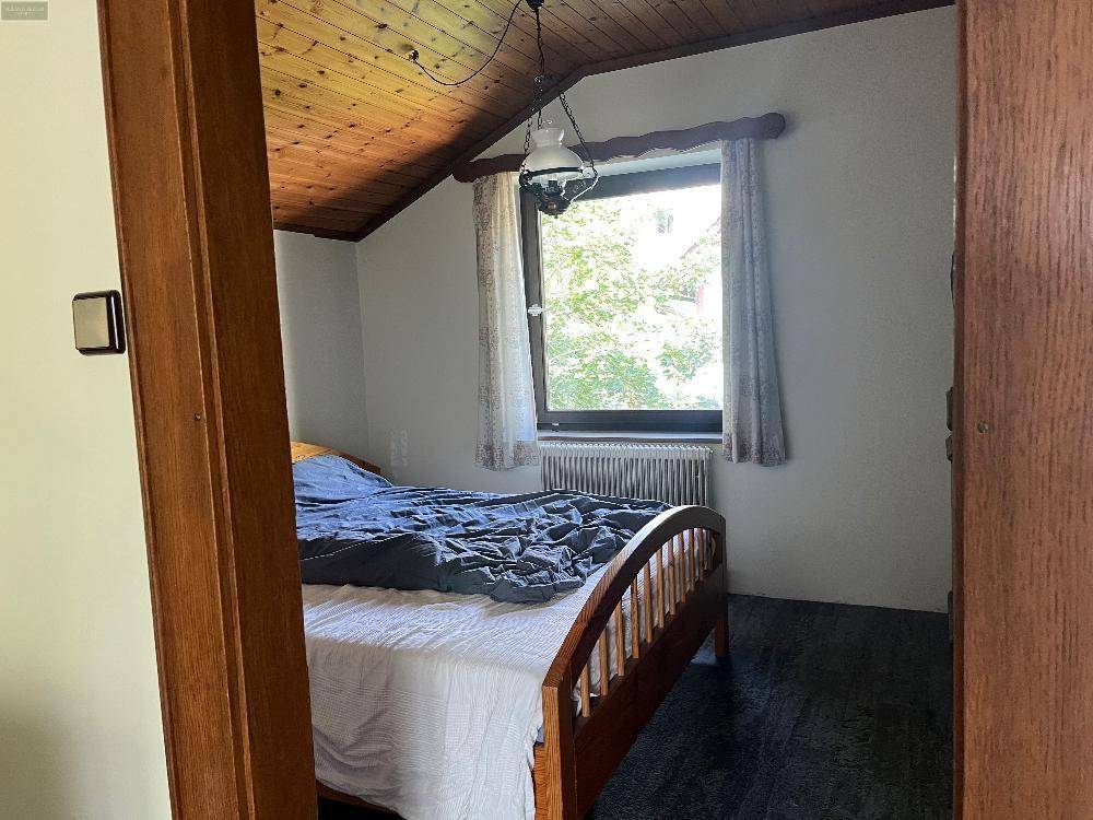 Gemütliches Schlafzimmer mit Holzdecke, Fenster und traditionellem Bett, das zum Entspannen einlädt.