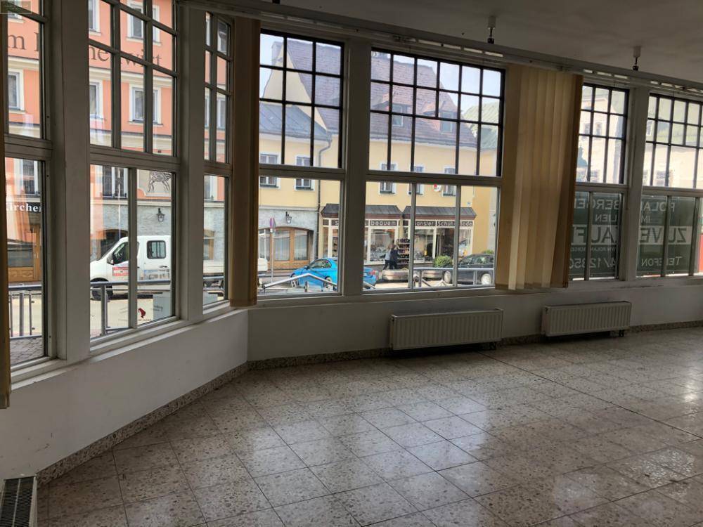 Geräumiger Innenraum mit Fliesenboden und weitem Blick auf die belebte Straße und Gebäude.