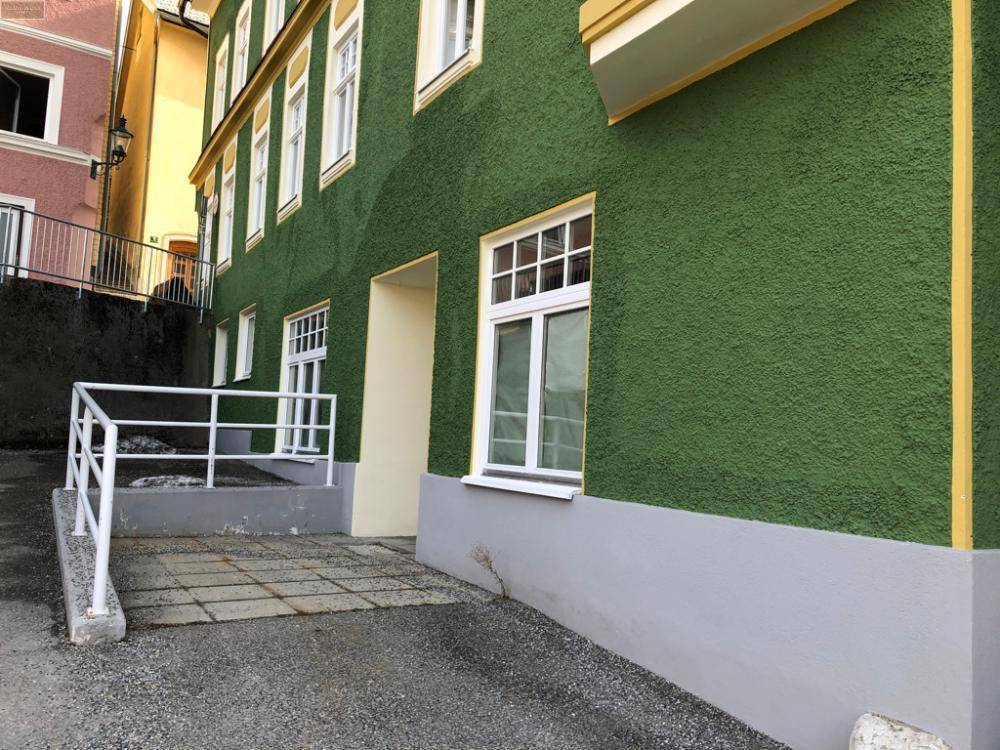 Seitenansicht des grünen Gebäudes mit einer Rampe, die zu einem Eingangsbereich führt.
