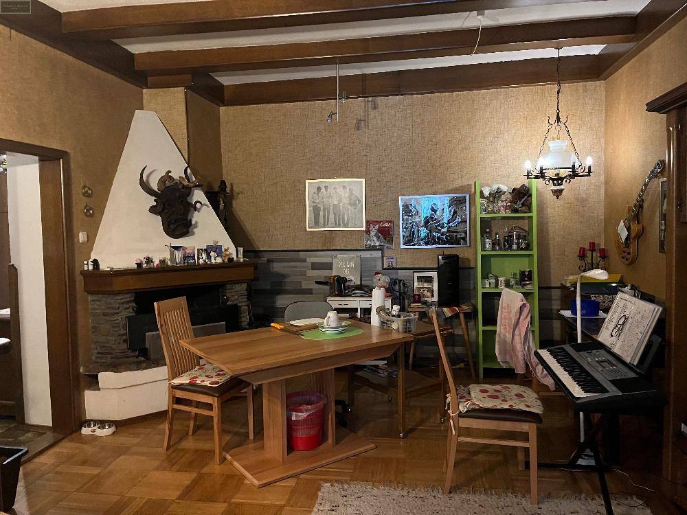 Wohnzimmer mit Holzboden, Kamin und traditionellen Möbeln, inklusive Geweihdekoration.