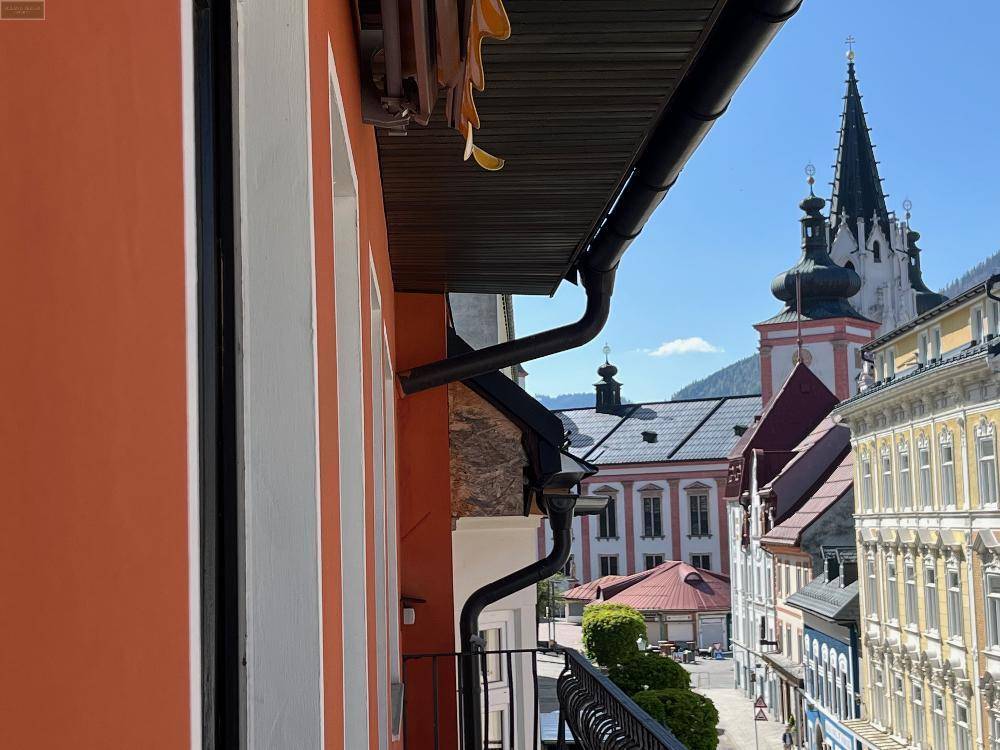 Blick vom Balkon auf die historische Stadt mit Kirchturm und umliegenden Gebäuden.