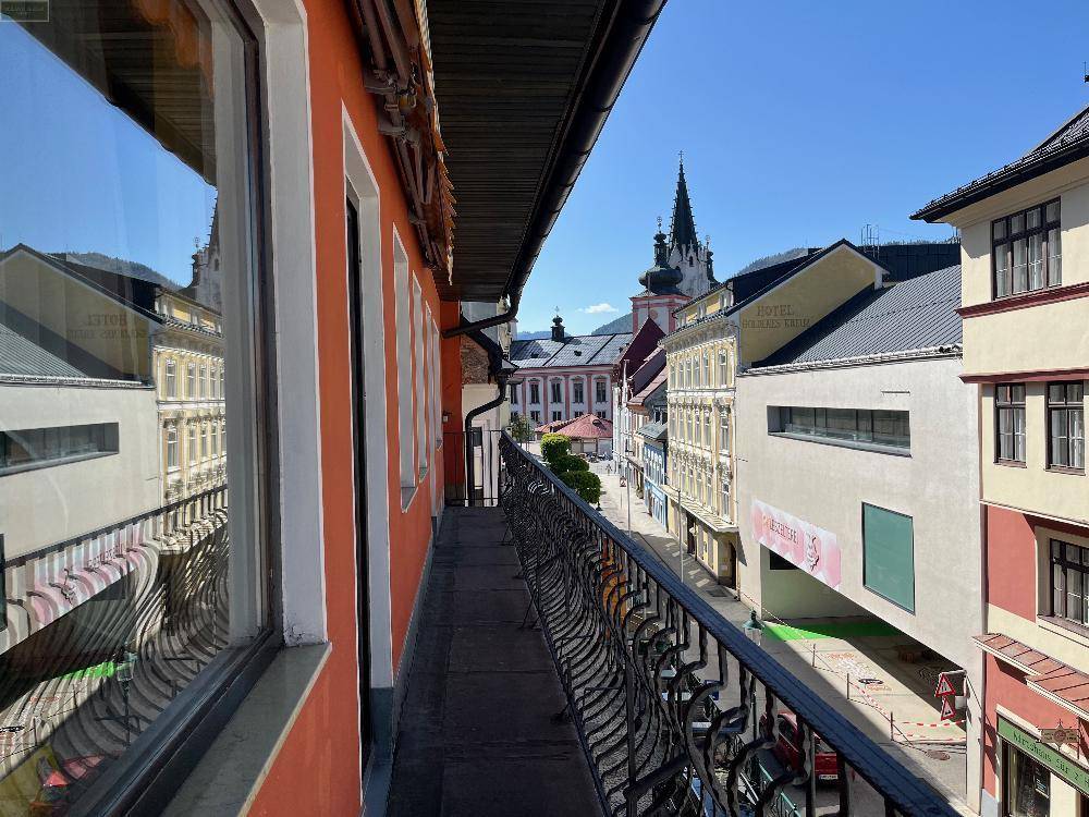 Langer Balkon mit schmiedeeisernem Geländer und Blick auf die historische Stadt.