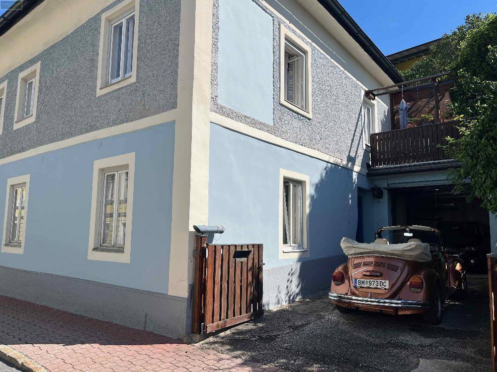 Seitenansicht des Gebäudes mit einem klassischen Auto auf dem gepflasterten Stellplatz.