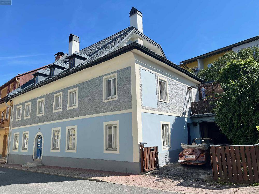 Historisches Gebäude mit blauer Fassade, vielen Fenstern und einem gepflasterten Vorplatz.
