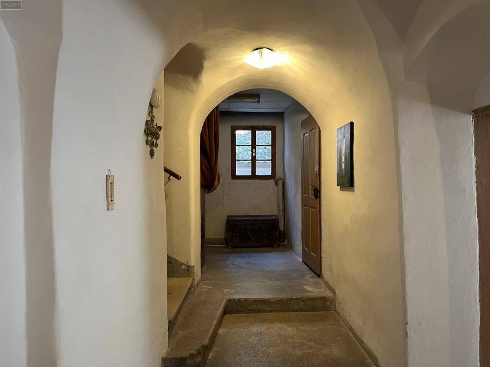 Gewölbter Flur mit rustikalem Charme, einem kleinen Fenster und traditioneller Einrichtung.