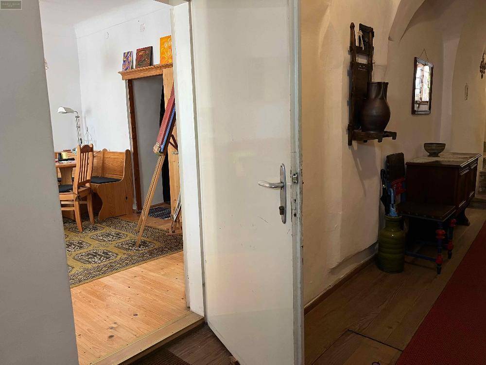 Blick vom Flur in ein helles Zimmer mit Holzboden und traditionellen Möbeln.