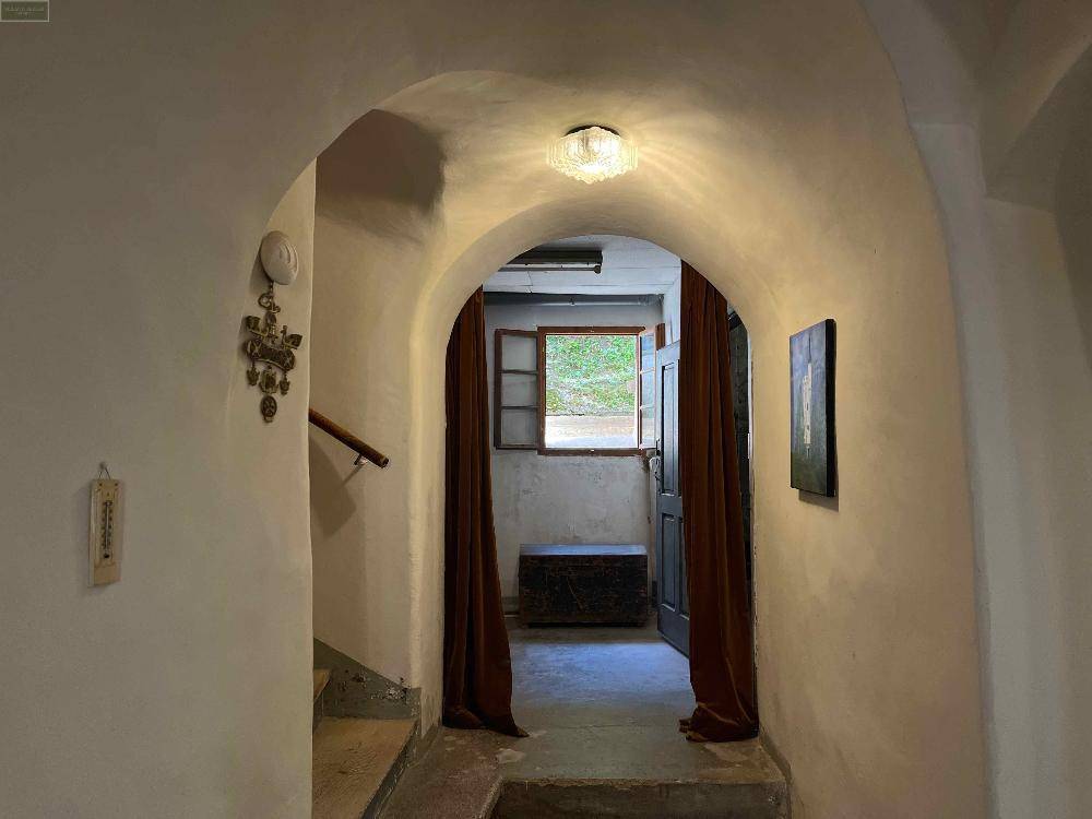Gewölbter Flur mit rustikalem Charme, einem kleinen Fenster und traditioneller Einrichtung.
