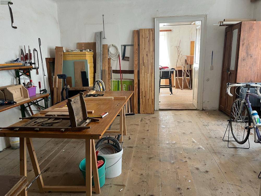 Großer Werkstattraum mit Holzboden, Werkbänken und verschiedenen Materialien.
