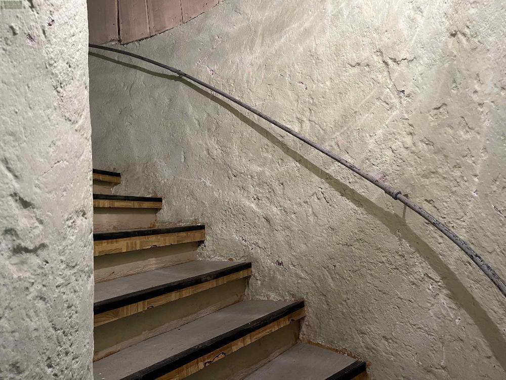 Detailansicht einer Treppe mit rauen Wänden und einem einfachen Handlauf.