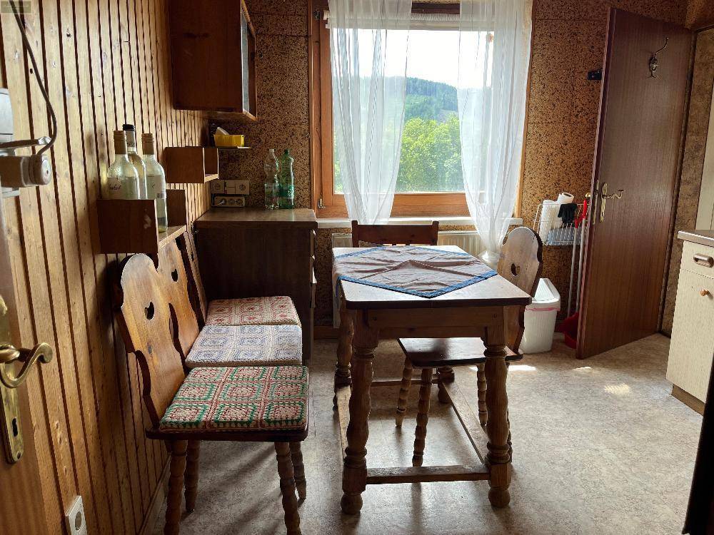 Kleine Essküche mit rustikalen Holzmöbeln und Fensterblick auf die grüne Landschaft.