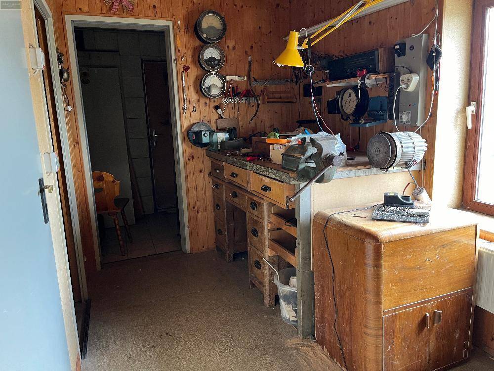 Werkstatt oder Hobbyraum mit Werkbank, verschiedenen Werkzeugen und Holzvertäfelung.