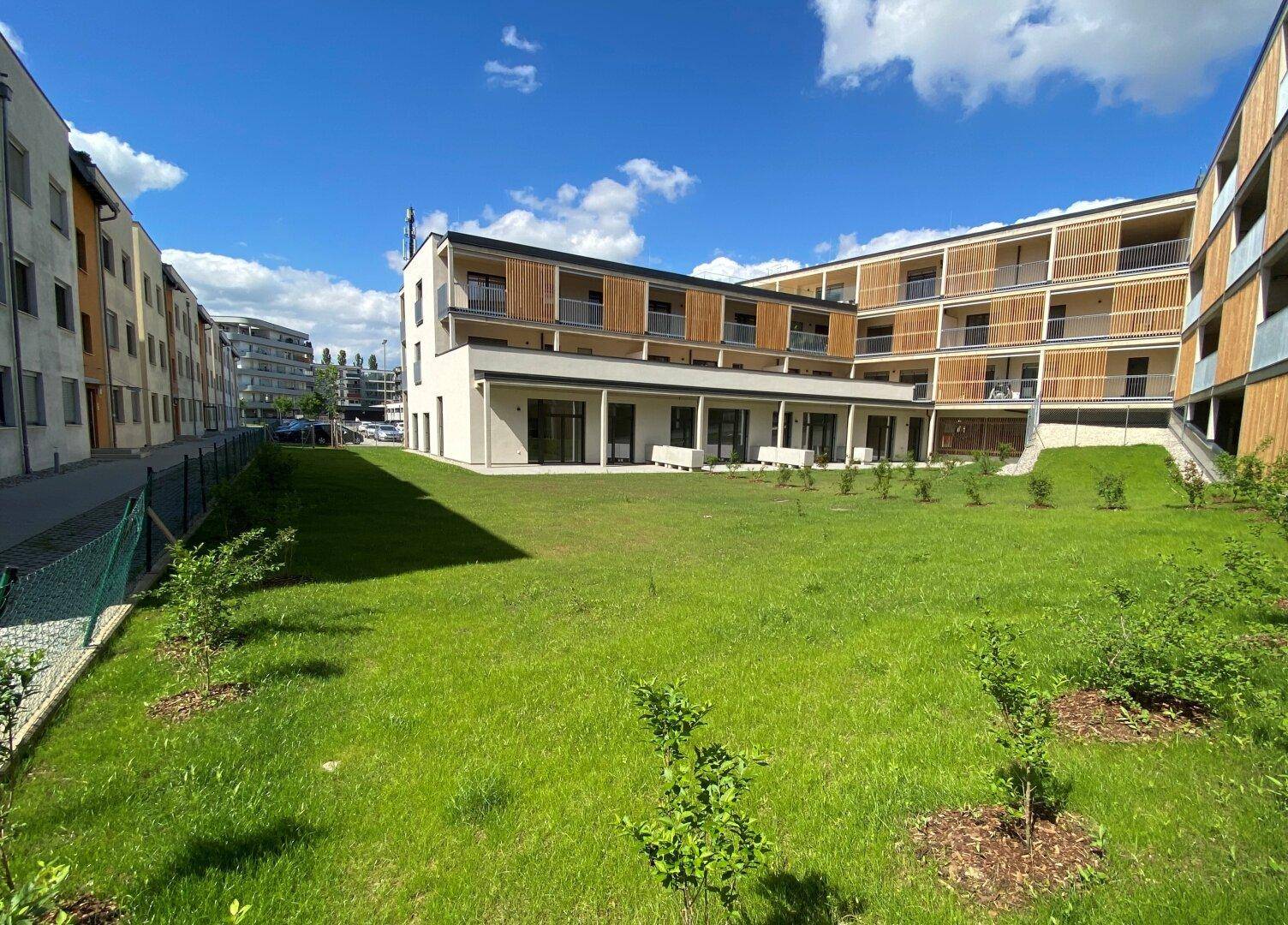 Weitläufige Außenansicht eines modernen Wohnkomplexes mit gepflegten Grünflächen.