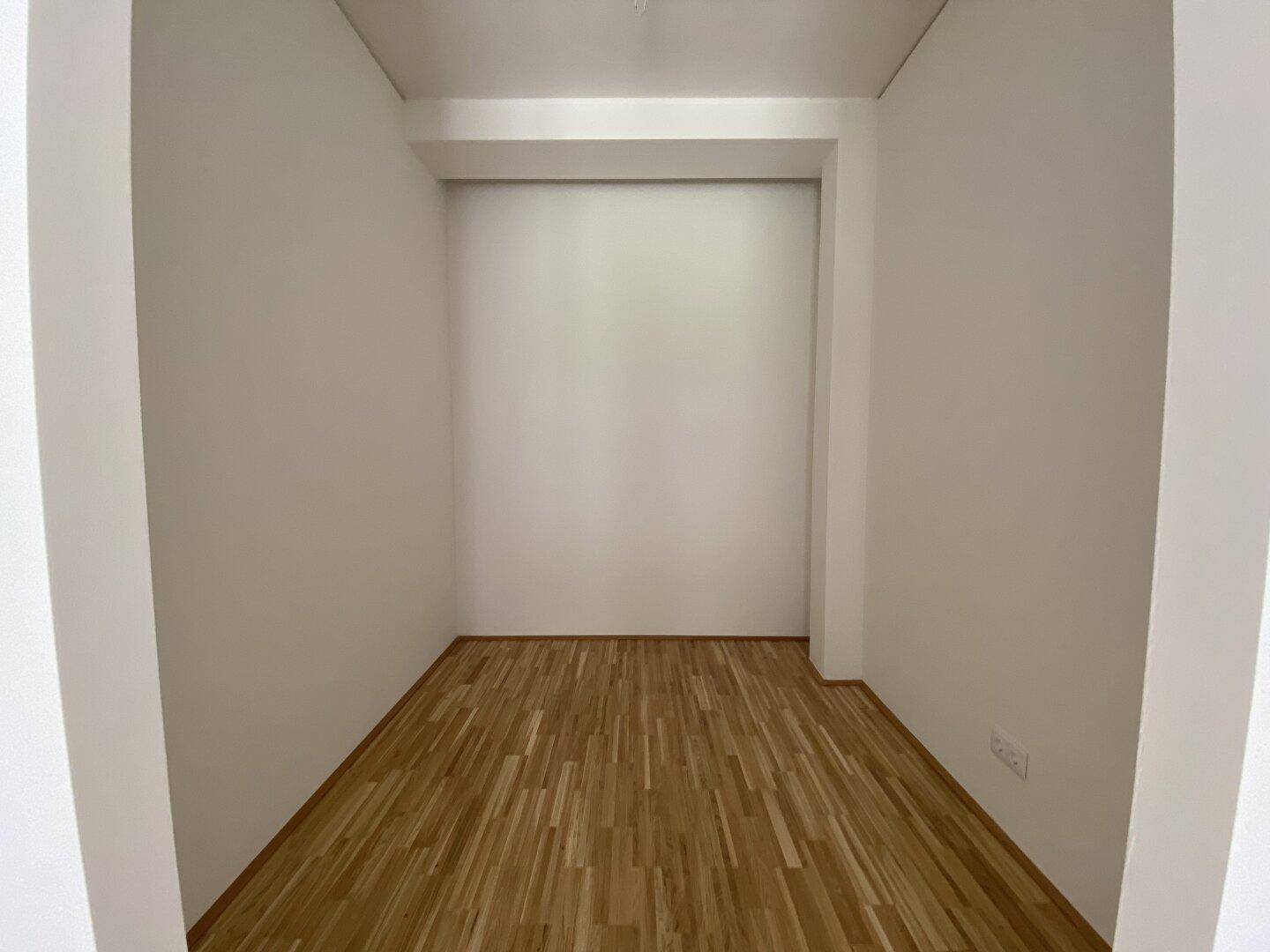 Kleiner, leerer Raum mit Holzparkett, ideal als Abstellraum oder begehbarer Kleiderschrank.