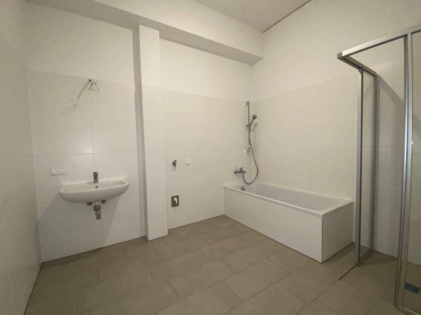 Geräumiges Badezimmer mit Badewanne, Dusche und Waschbecken, hell gefliest.
