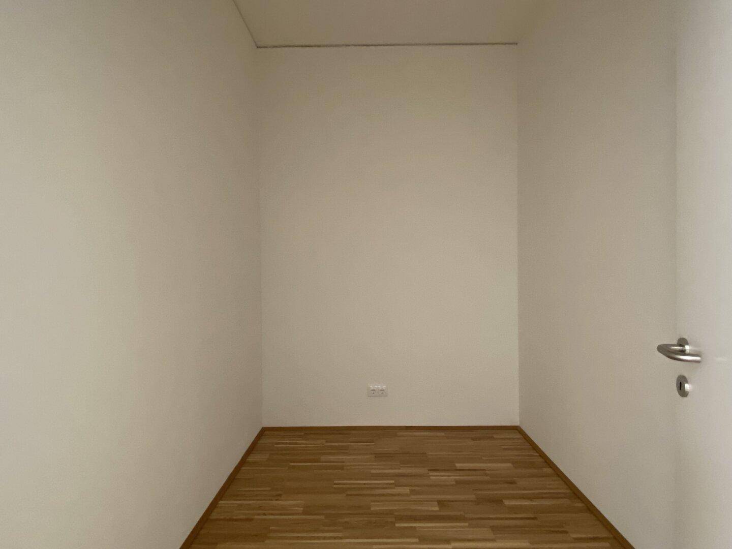 Kleiner, leerer Raum mit Parkettboden, ideal als Abstellraum oder begehbarer Kleiderschrank.