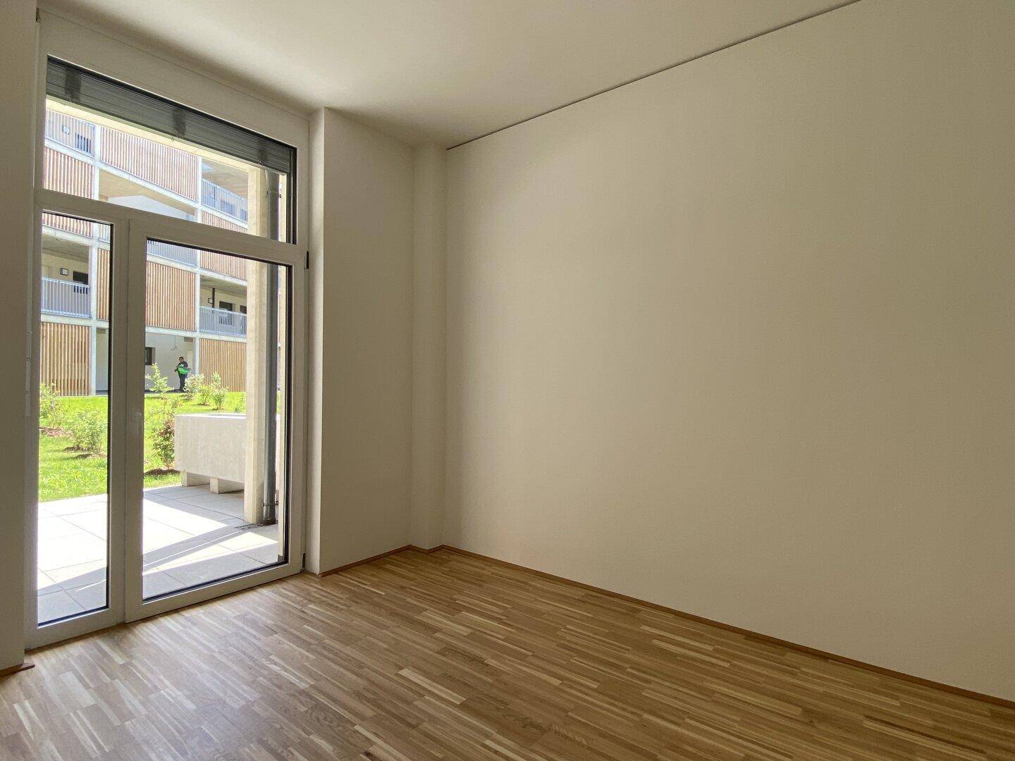 Helles Schlafzimmer mit Parkettboden und direktem Zugang zu einem privaten Außenbereich.