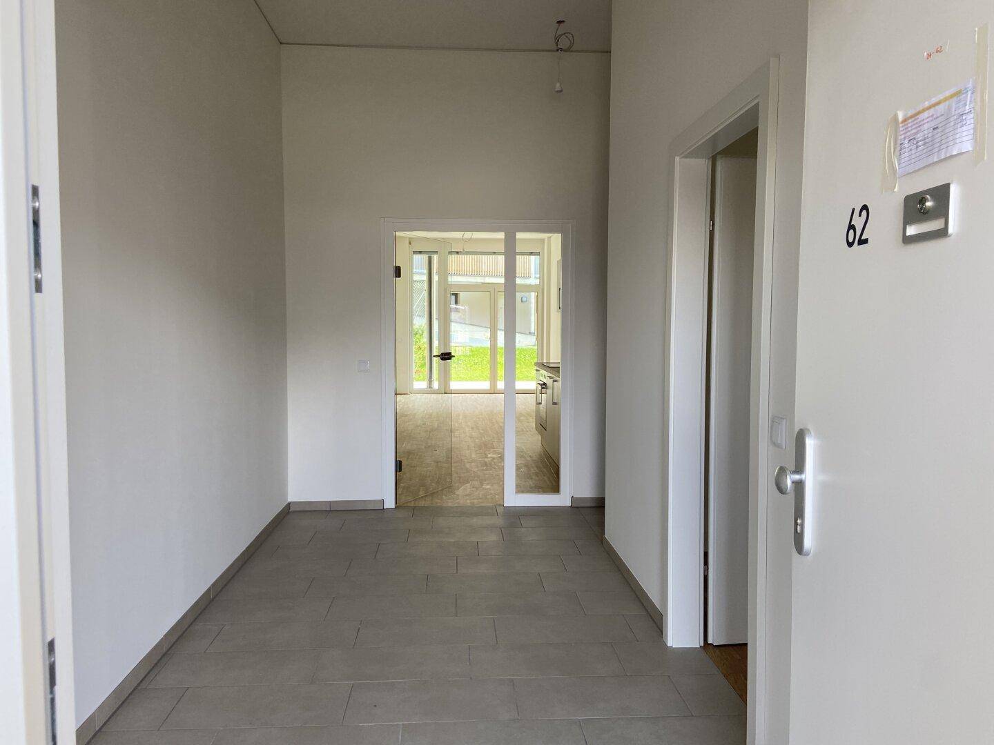 Eingangsbereich mit Fliesenboden, der zu den Wohnräumen und der Küche führt.