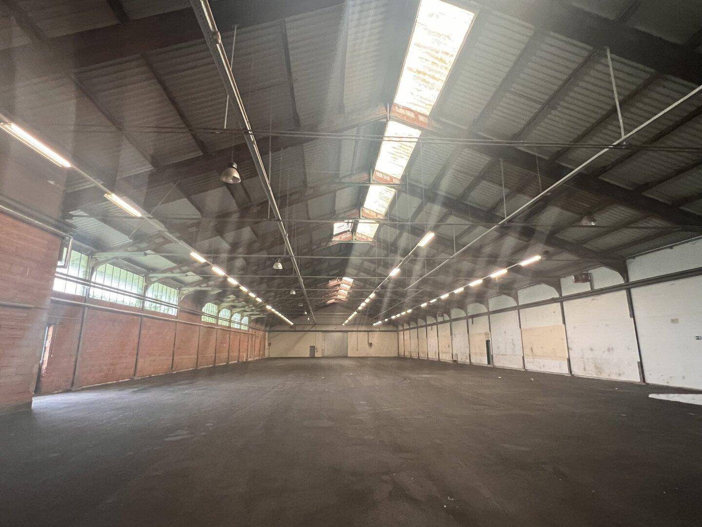 Geräumige Lagerhalle mit hohen Decken, Oberlichtern und industriellem Charme.