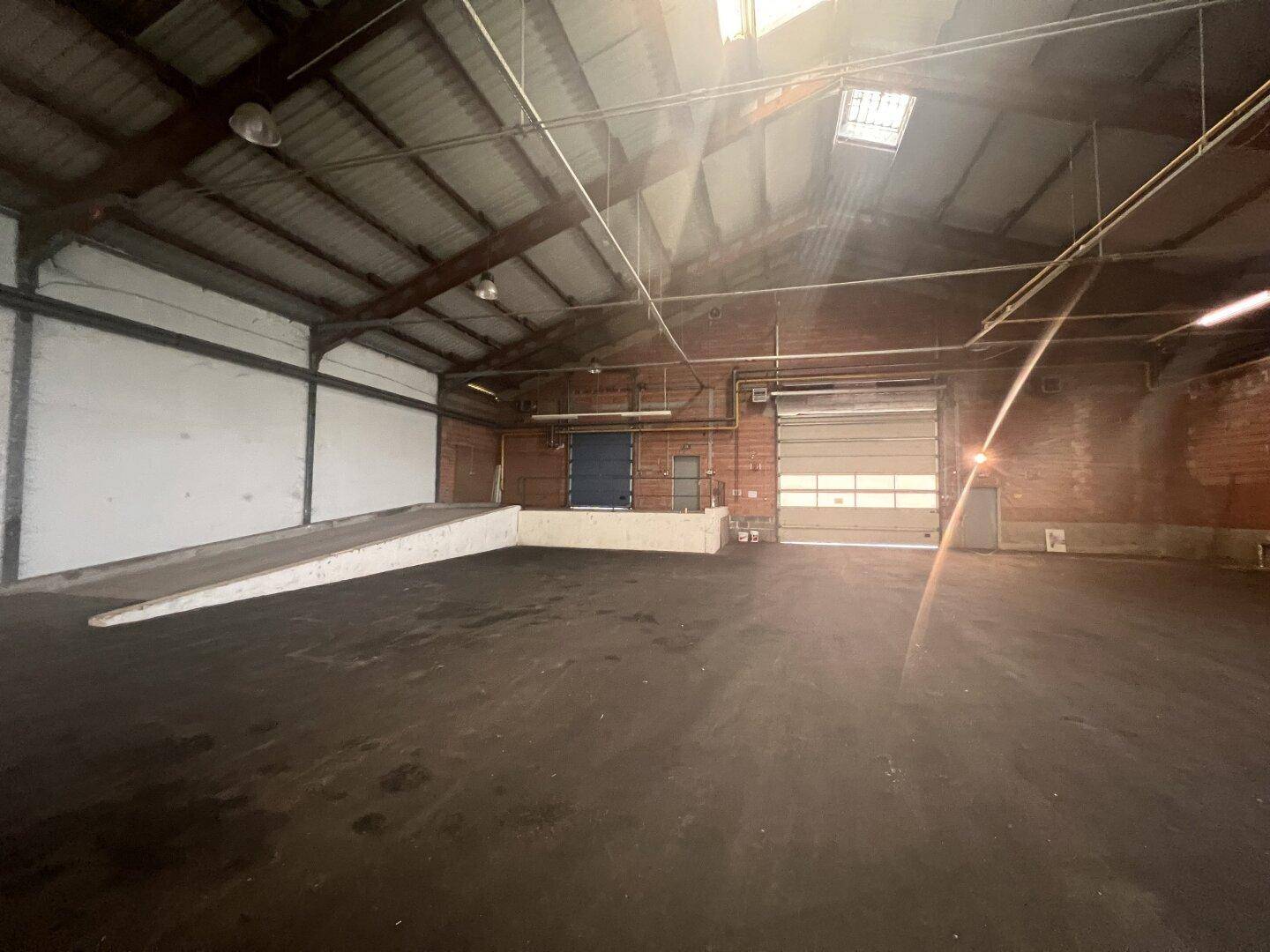 Innenansicht einer Lagerhalle mit Laderampe, Rolltoren und natürlichem Lichteinfall.