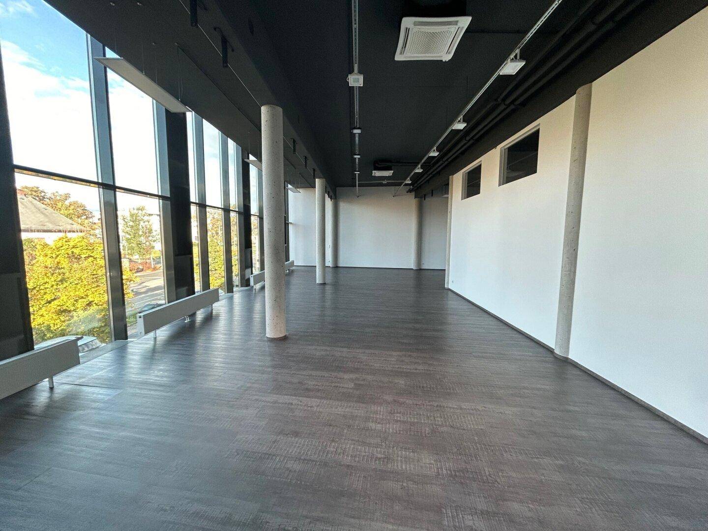 Heller und geräumiger Bürobereich mit großen Fenstern und Blick ins Grüne.