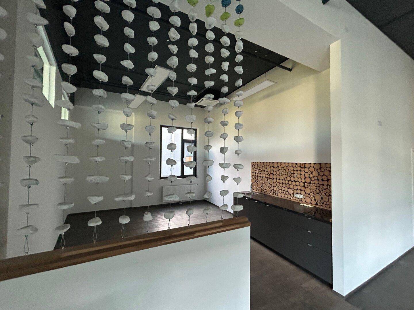 Empfangsbereich mit dekorativer Wandverkleidung aus Holz und modernen Hängeelementen.