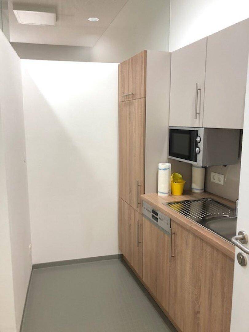 Kompakte Küchenzeile mit Holzschränken, integrierter Mikrowelle, Spüle und Geschirrspüler, ideal für kleine Räume.